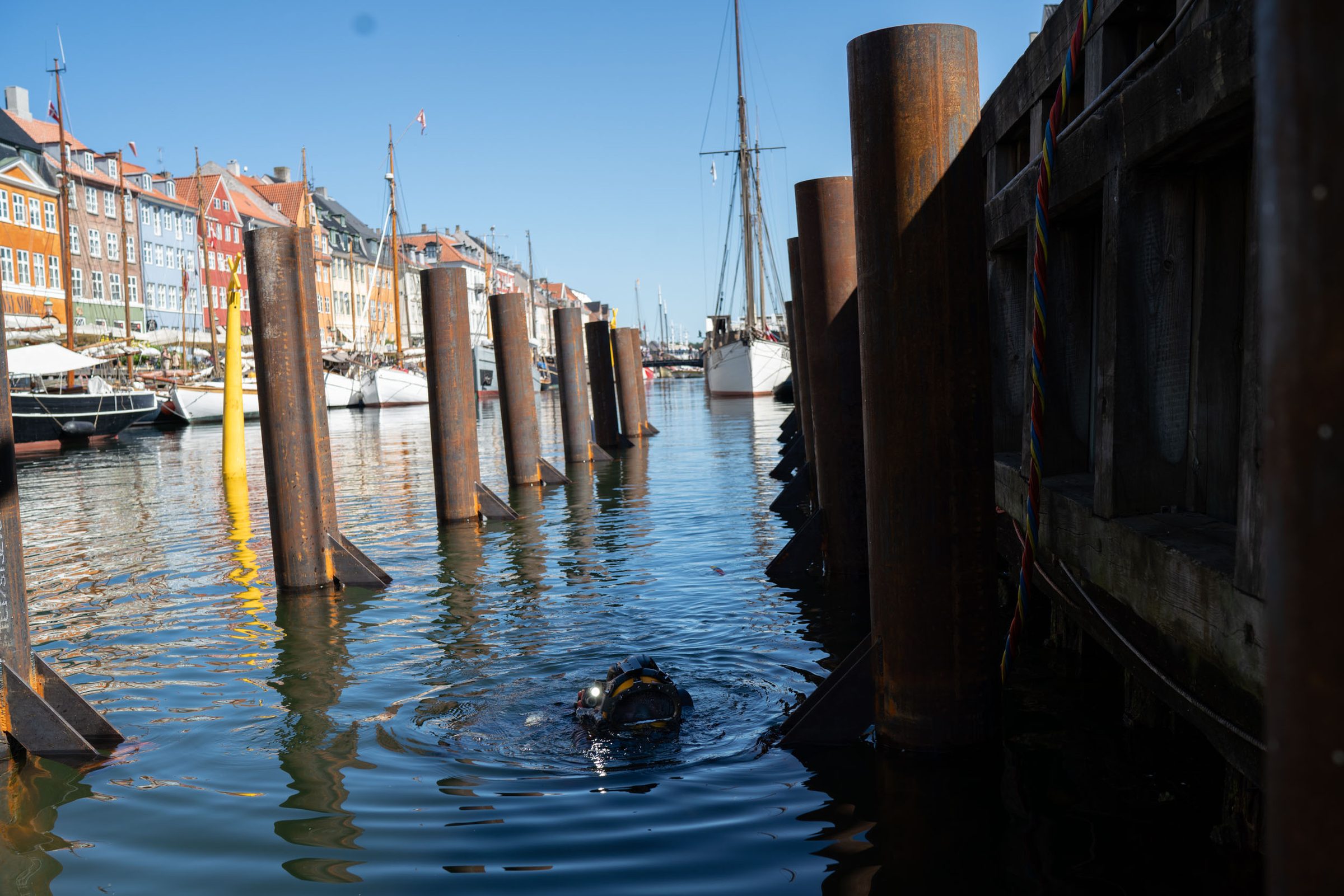 Erhvervsdykker i vandet mellem stålpæle ved Nyhavn